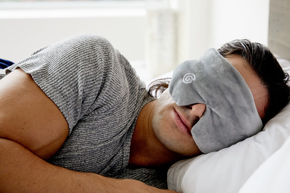 a man napping in bed with a gravity blankets eyemask