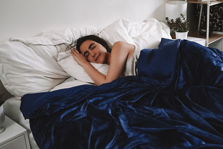 a woman sleeping under a weighted blanket