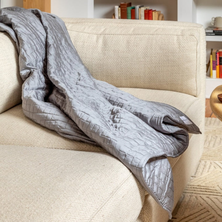 A Classic Grey Gravity Weighted Cooling Blanket draped over a sofa - #color_classic-grey