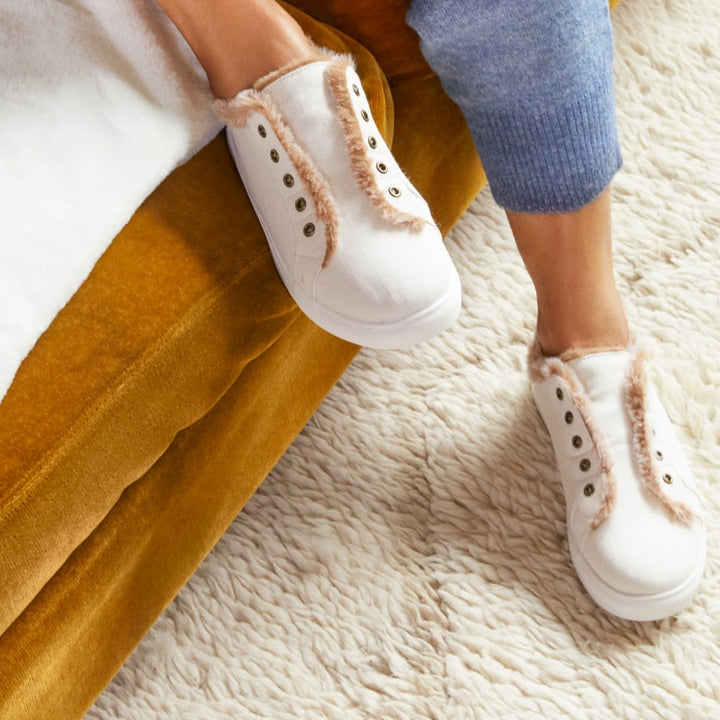 Closeup of woman's feet wearing off white faux fur lined slippers #color_off-white