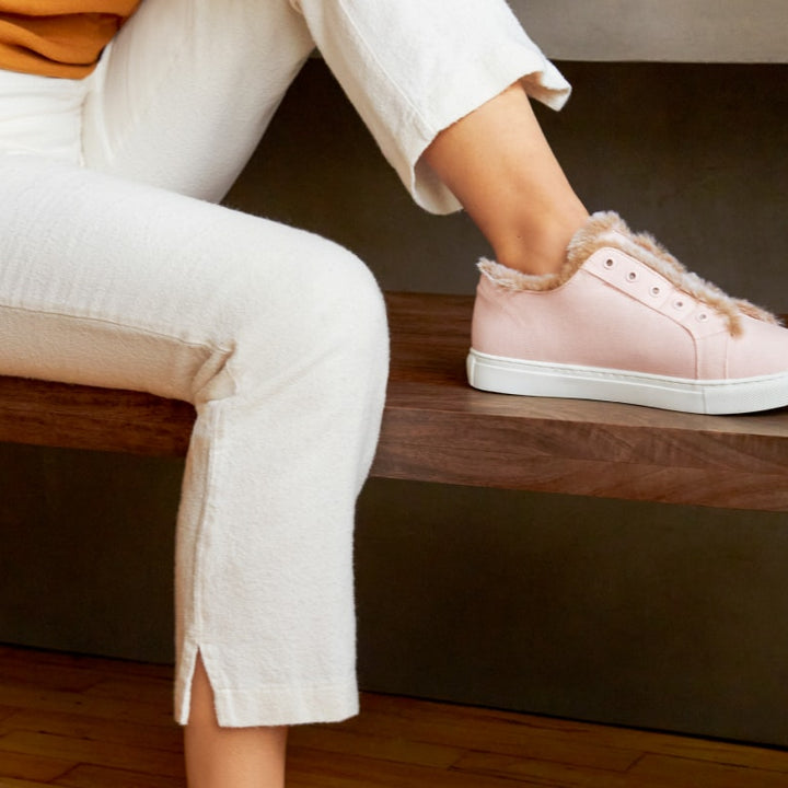 Closeup of a foot placed on a bench wearing pink faux fur lined slippers #color_pink