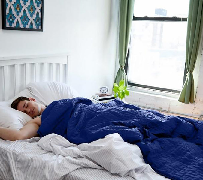 a man sleeping under a blue weighted blanket