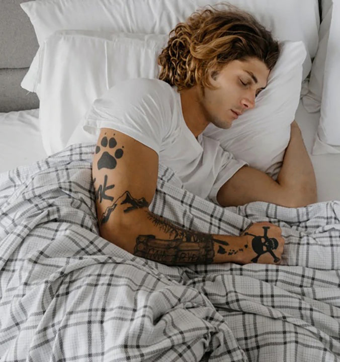 a man sleeping under a striped weighted blanket