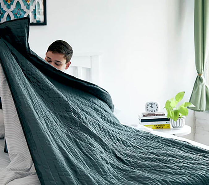 a woman pulling a green weighted blanket over herself