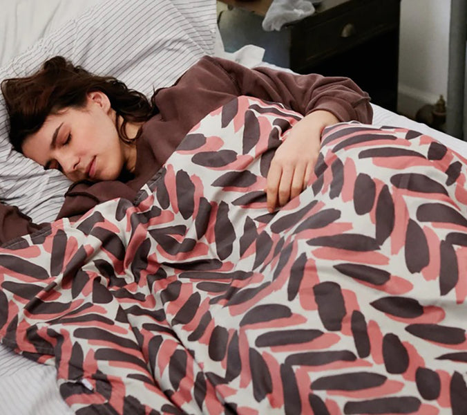 a woman sleeping under a chevron patterned weighted blanket