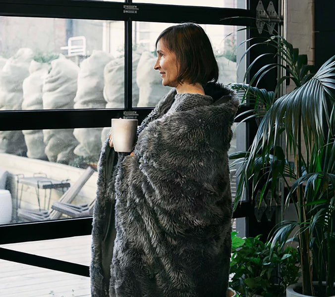 a woman with a mug wrapped in a fuzzy weighted blanket