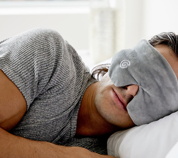 a man napping in bed with a gravity blankets eyemask