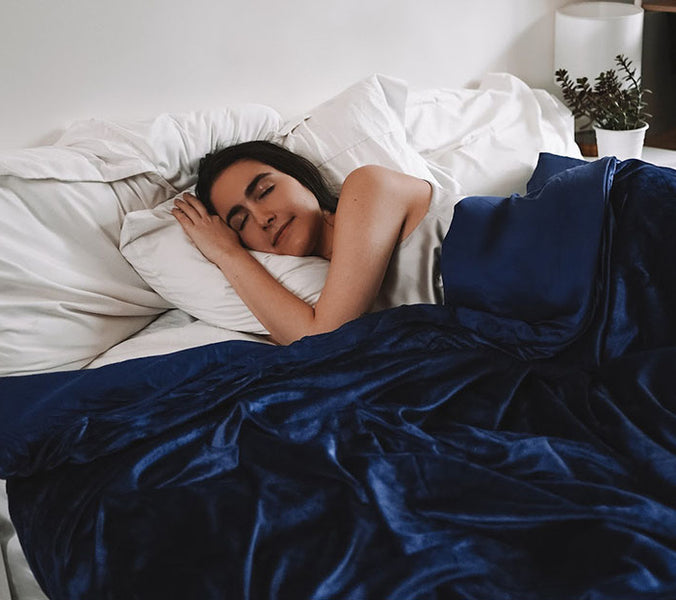a woman sleeping under a weighted blanket